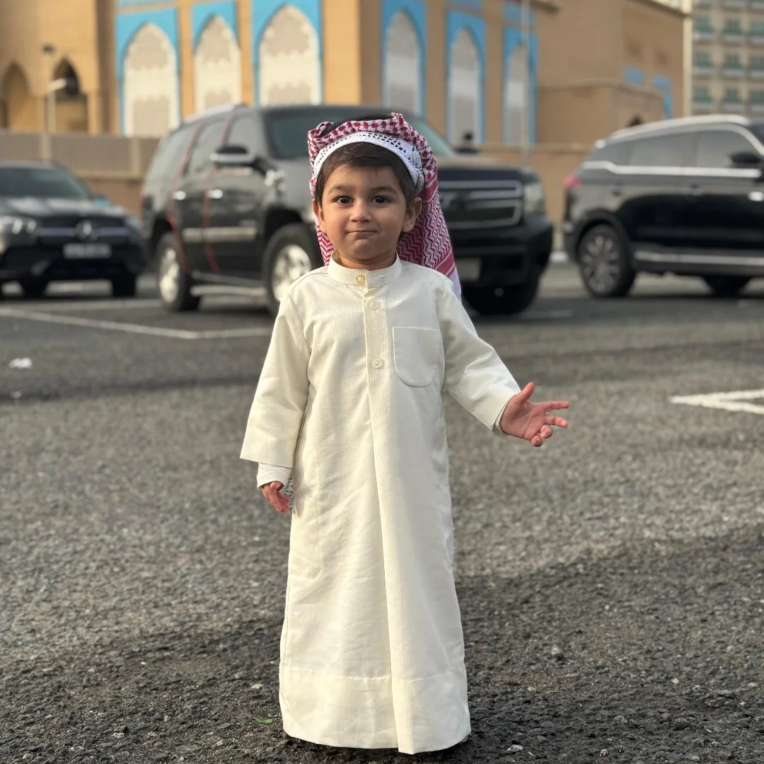 Young boy wearing a premium custom-made children's Dishdasha tailored by Maqs Al-Sindbad Tailors.